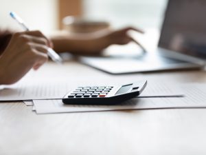 Closeup of female bookkeeper work at desk on calculator laptop